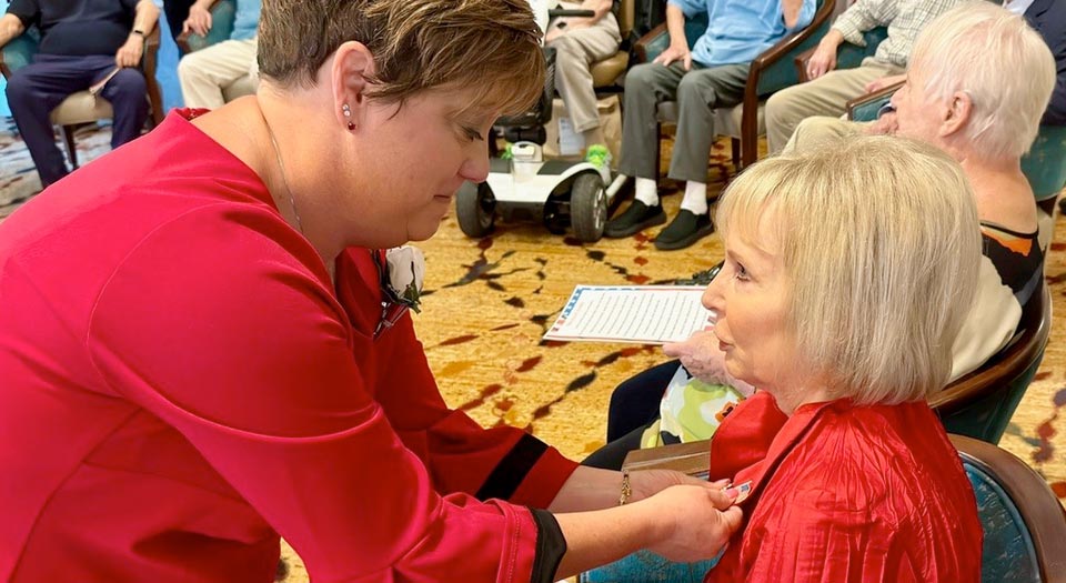 A volunteer in a red shirt pins a Veteran.